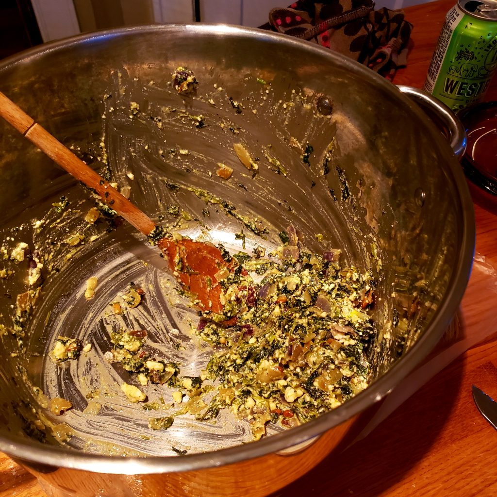 large pot with spinach mixture and wooden spoon