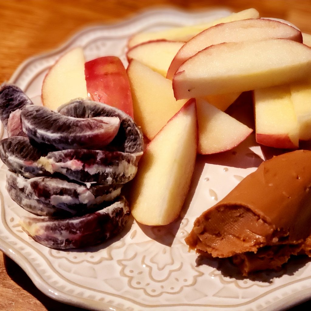 plate with apples, peanut butter, and blood orange slices. 