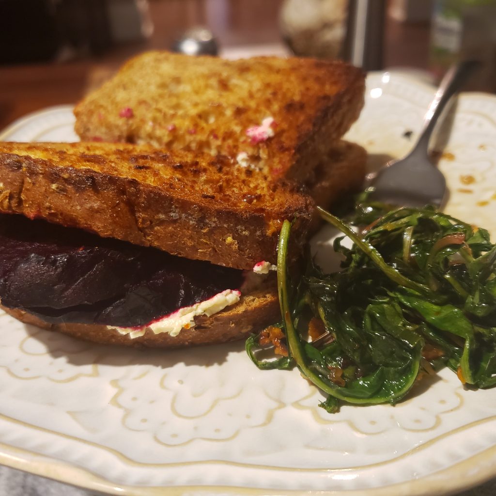 sandwich with beets and a side of greens