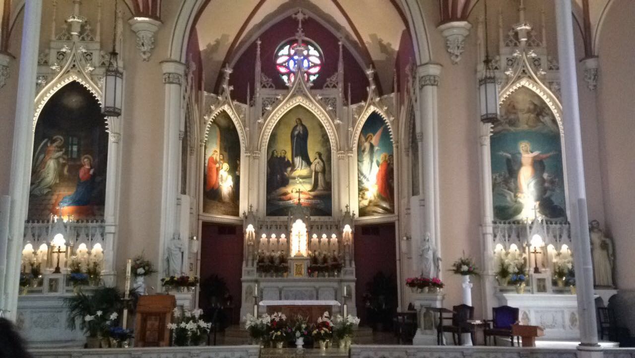 inside of the Holy Cross-Immaculata Church alter. Three paintings in the middle above candles.