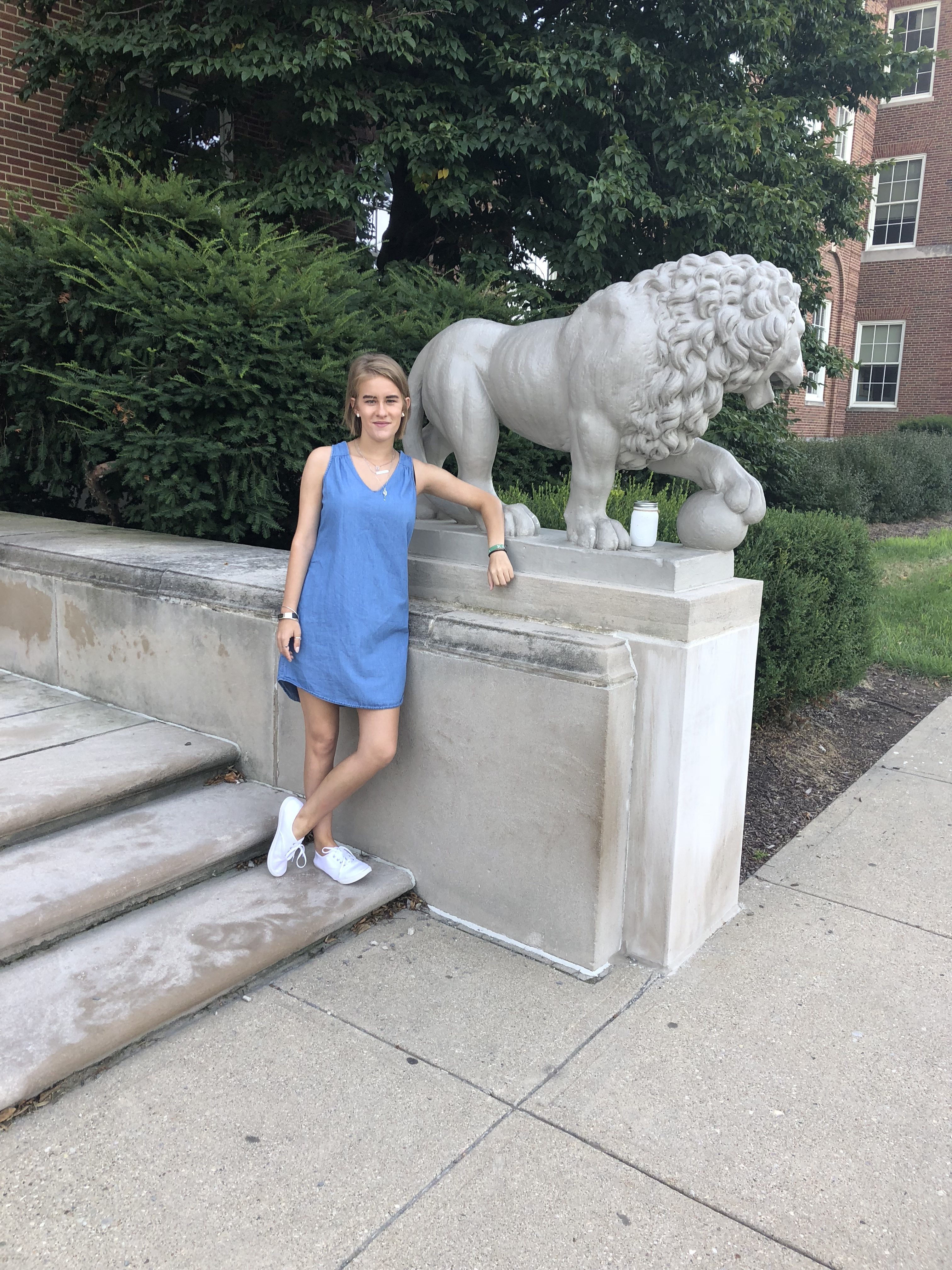 woman standing on stairs next to stone lion