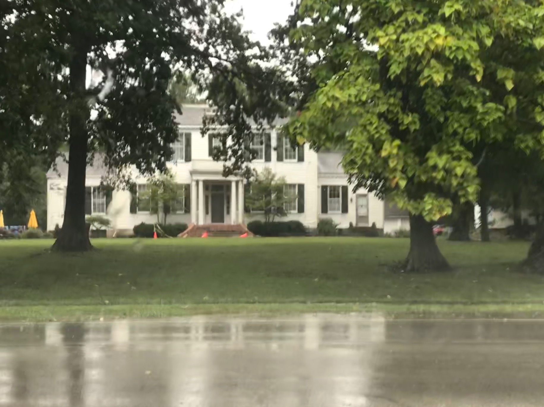 white house in front of water with big trees