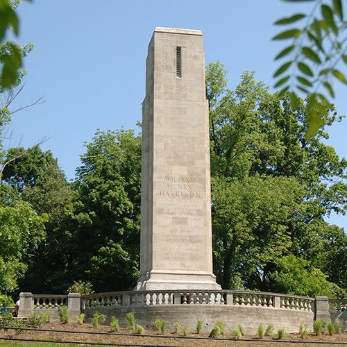 large, square, vertical monument with trees in background