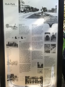 White historical marker with black and white images and black lettering explaining the past of Hyde Park Square