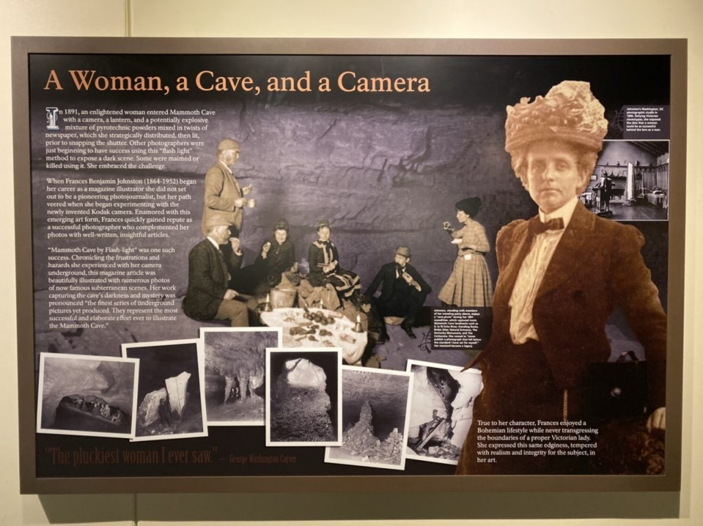 A poster titles “A woman, a cave, and a camera,” with pictures and text. The text talks about Frances Benjamin Johnston, and the pictures include Johnston in period clothing, a picture of her crew consisting of four men and one woman, and several examples of her cave photography