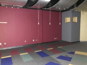 Dark show room that once showcased plastic moldings with vivid paint on the walls and vibrant carpet
