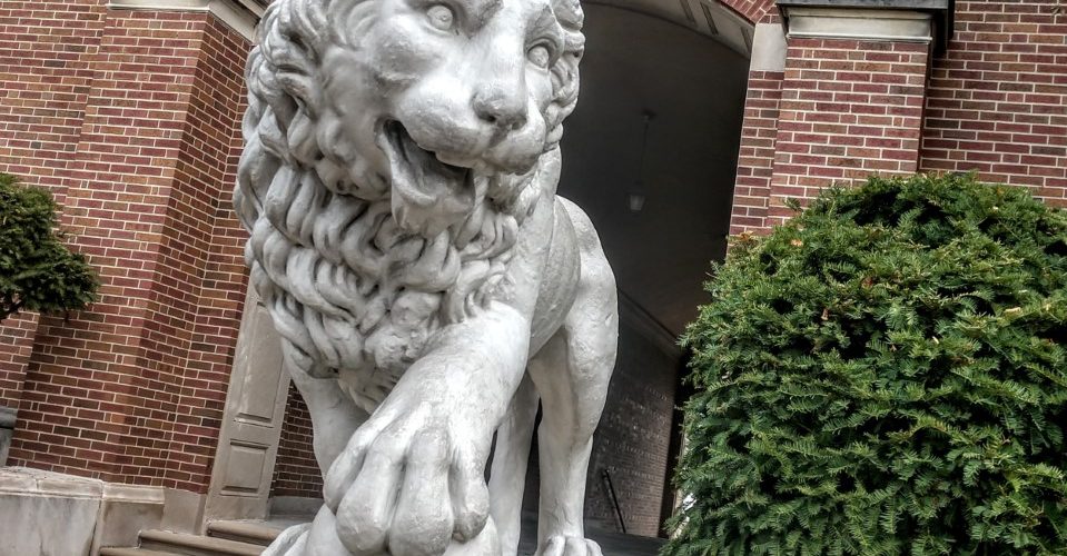 McMicken Hall lion, red brick building in background