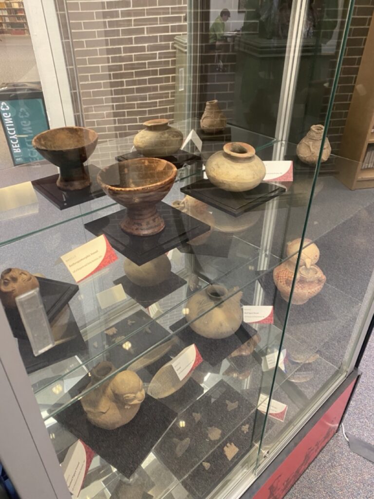 Glass case of clay pottery including Ecuadorian style bowls