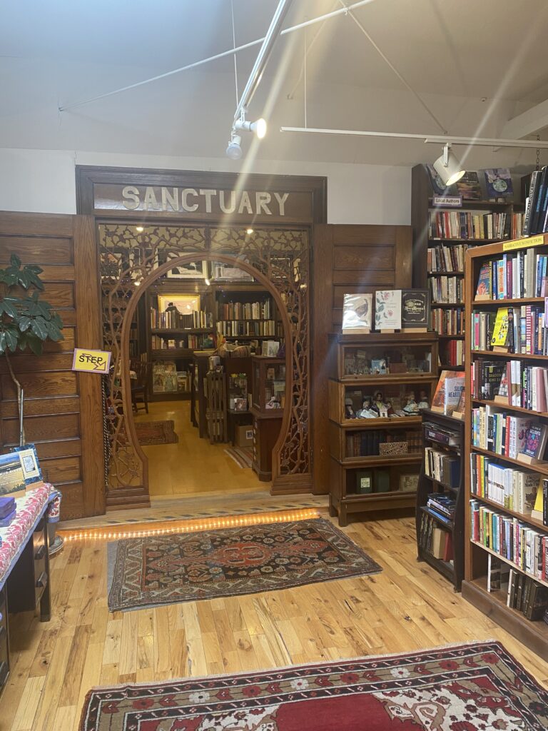 Arched doorway with "Sanctuary" above the entrance leading into room lined with bookshelves
