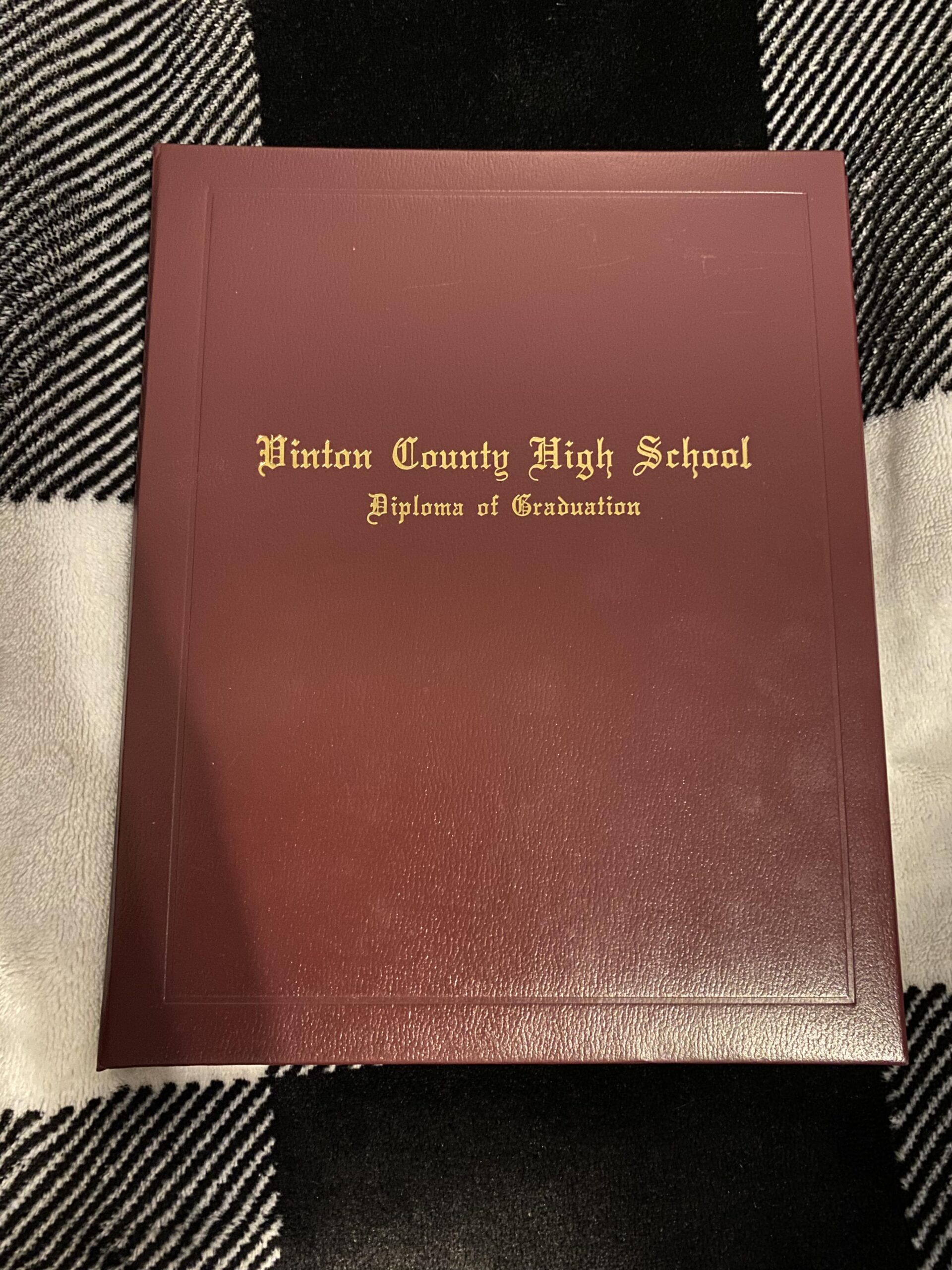 Maroon-binded front cover of a high school diploma.