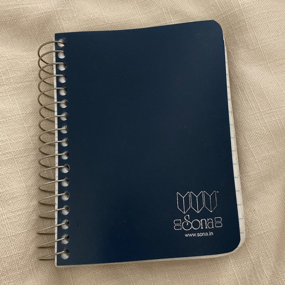 A navy blue notebook against a cream fabric