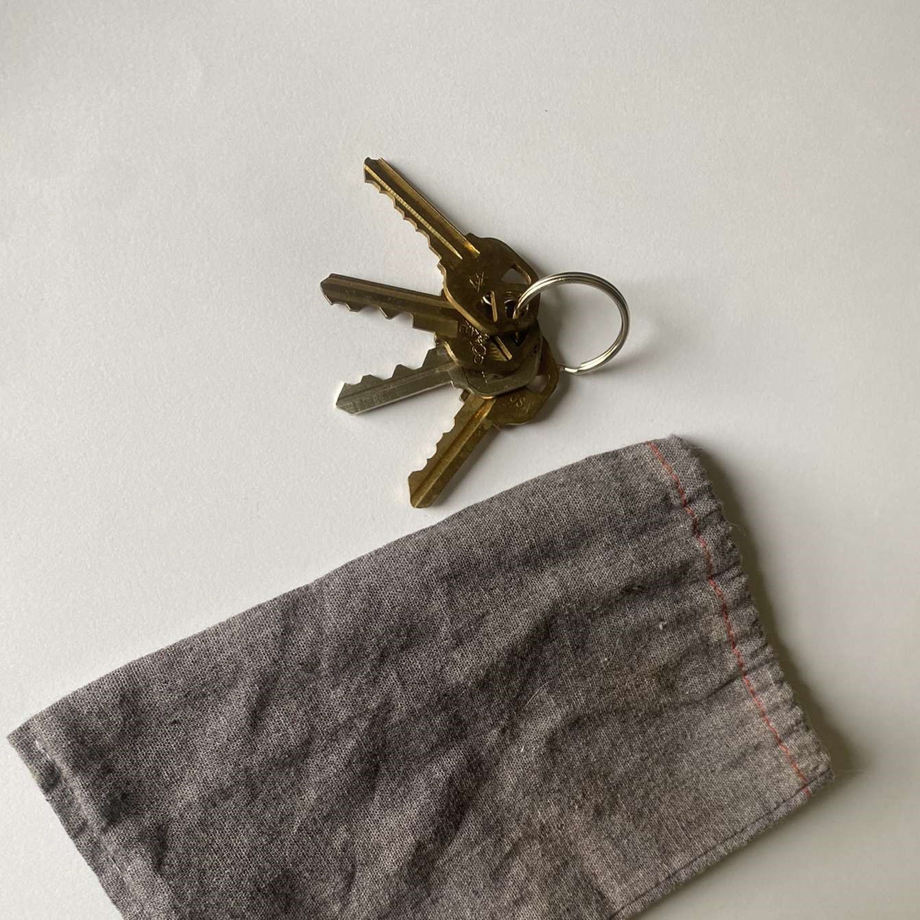 A set of four keys on a jump ring and the gray bag that they are kept in