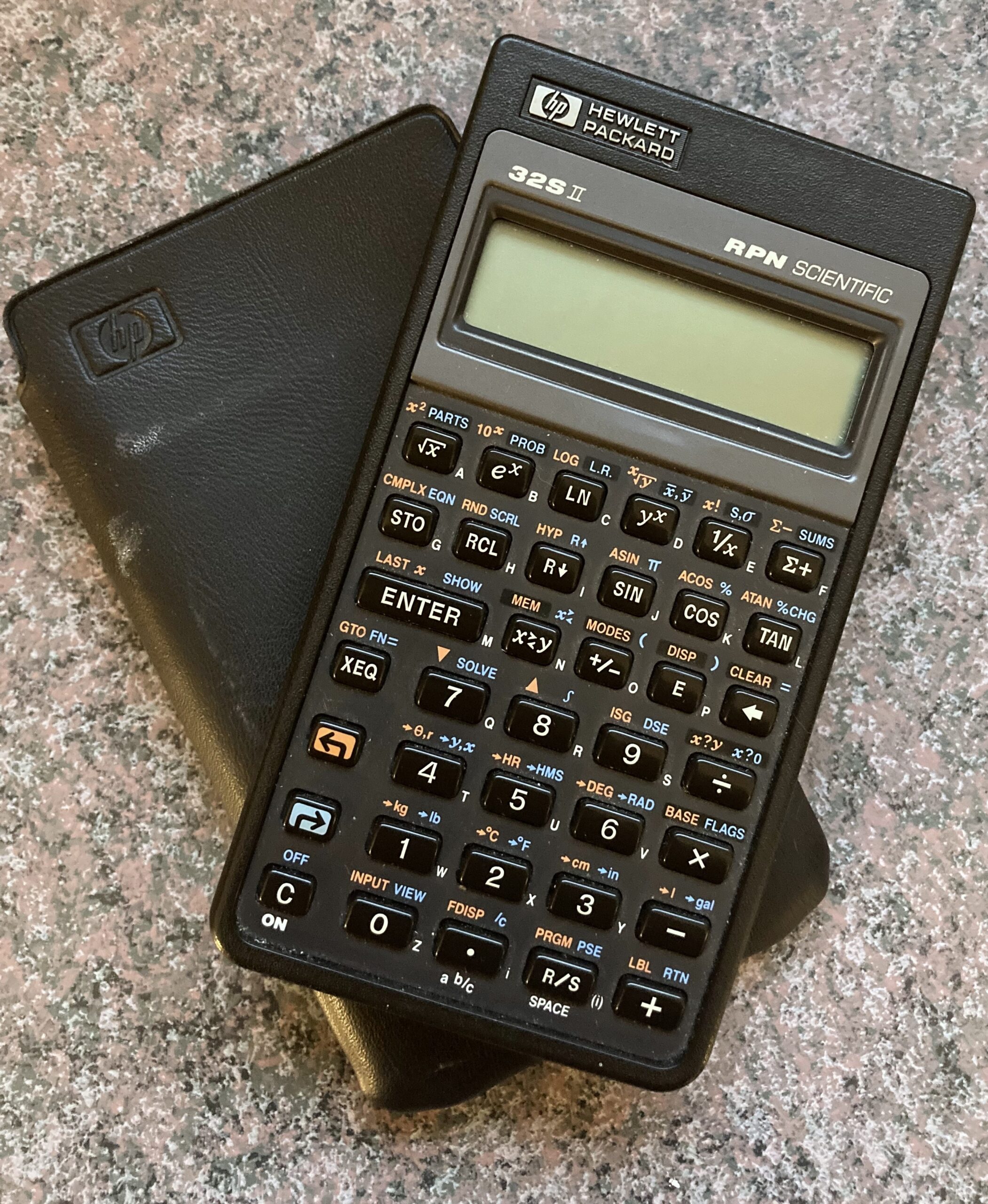 A black calculator on top of its case.