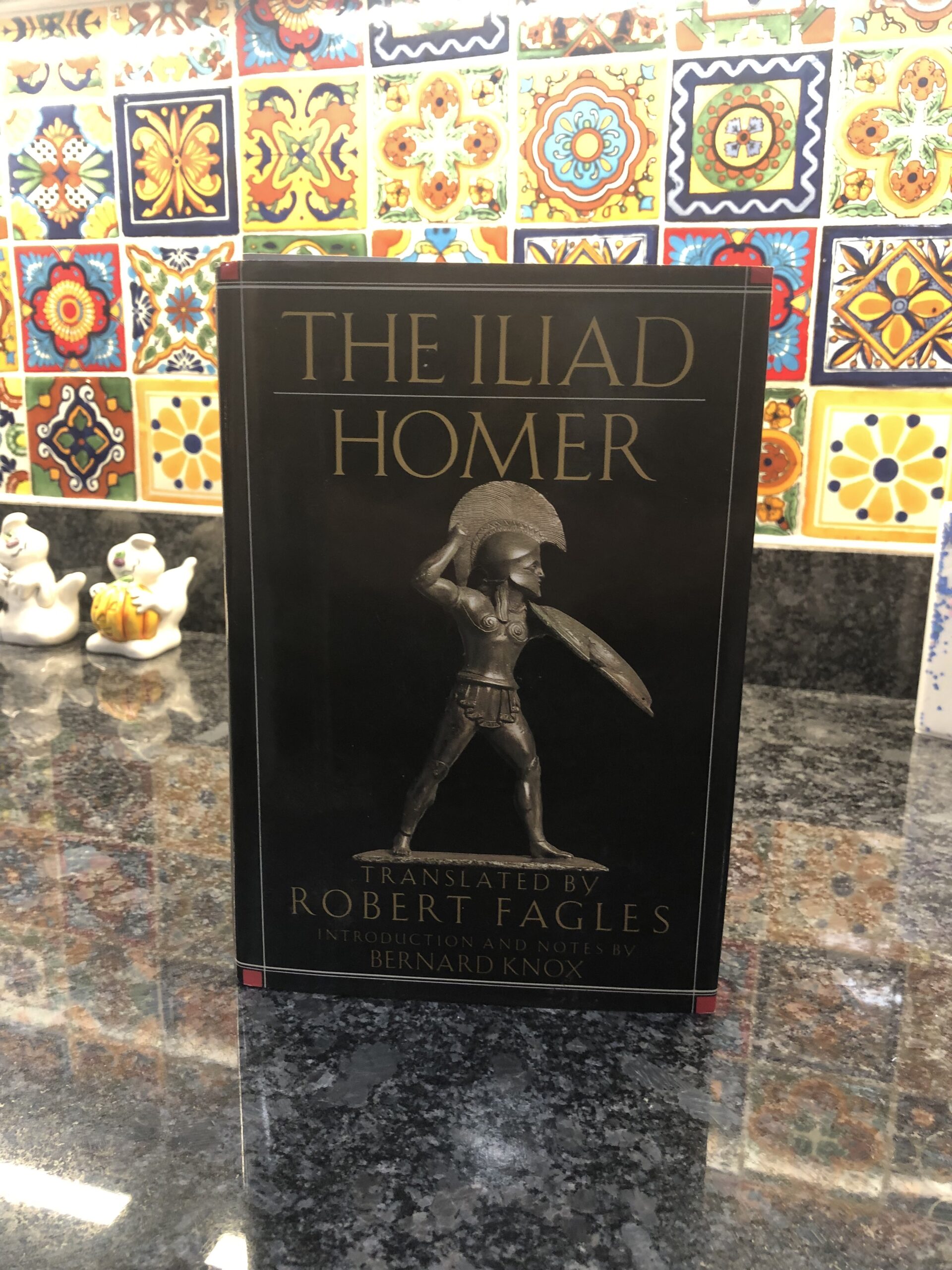 Front view of the Iliad. A black book with a hoplite displayed across the cover.