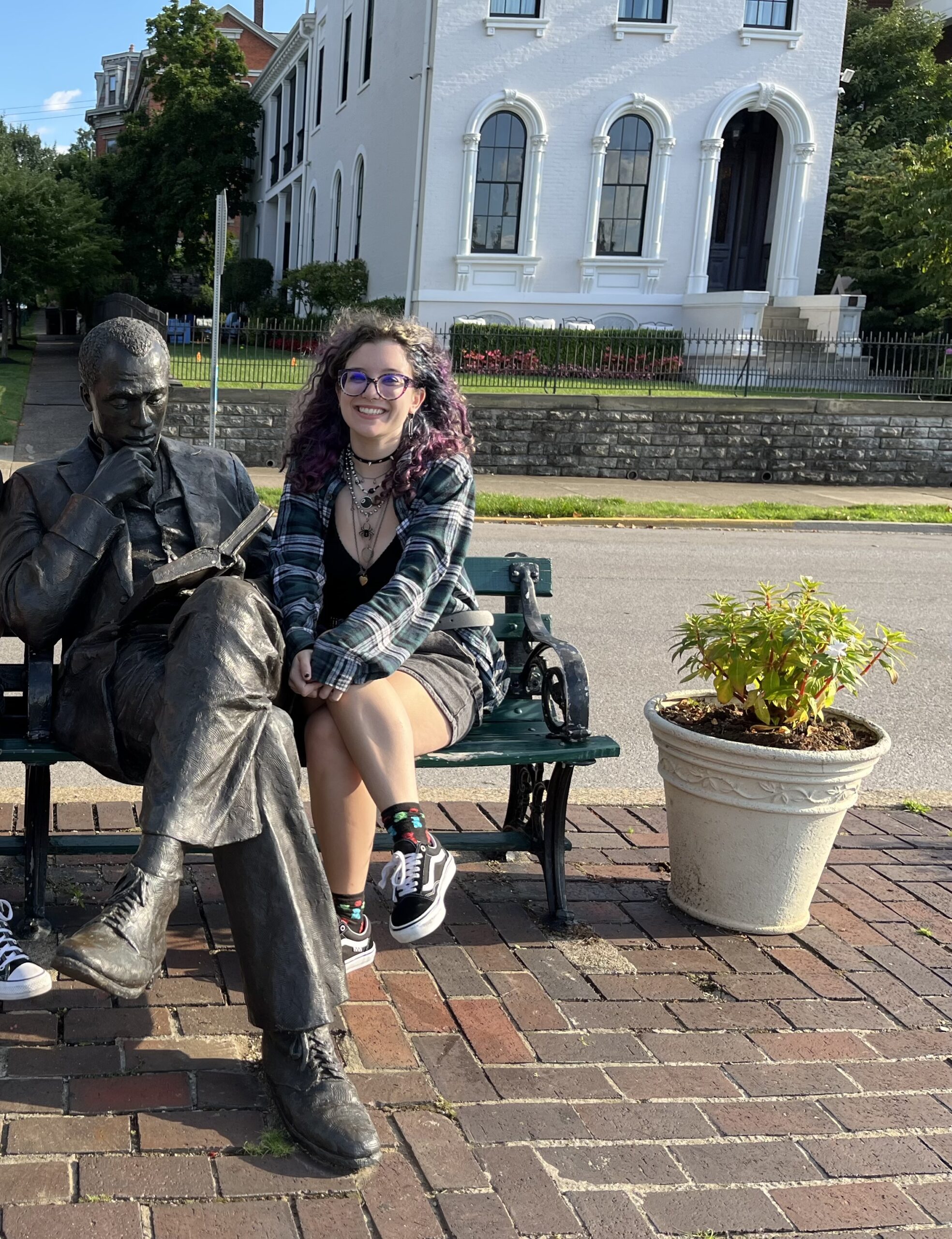 Madelyn Braun wearing vans sitting on a bench next to a statue