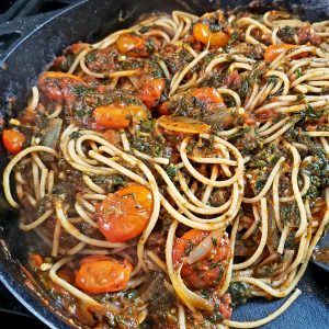 spaghetti with tomatoes and spinach in a pan